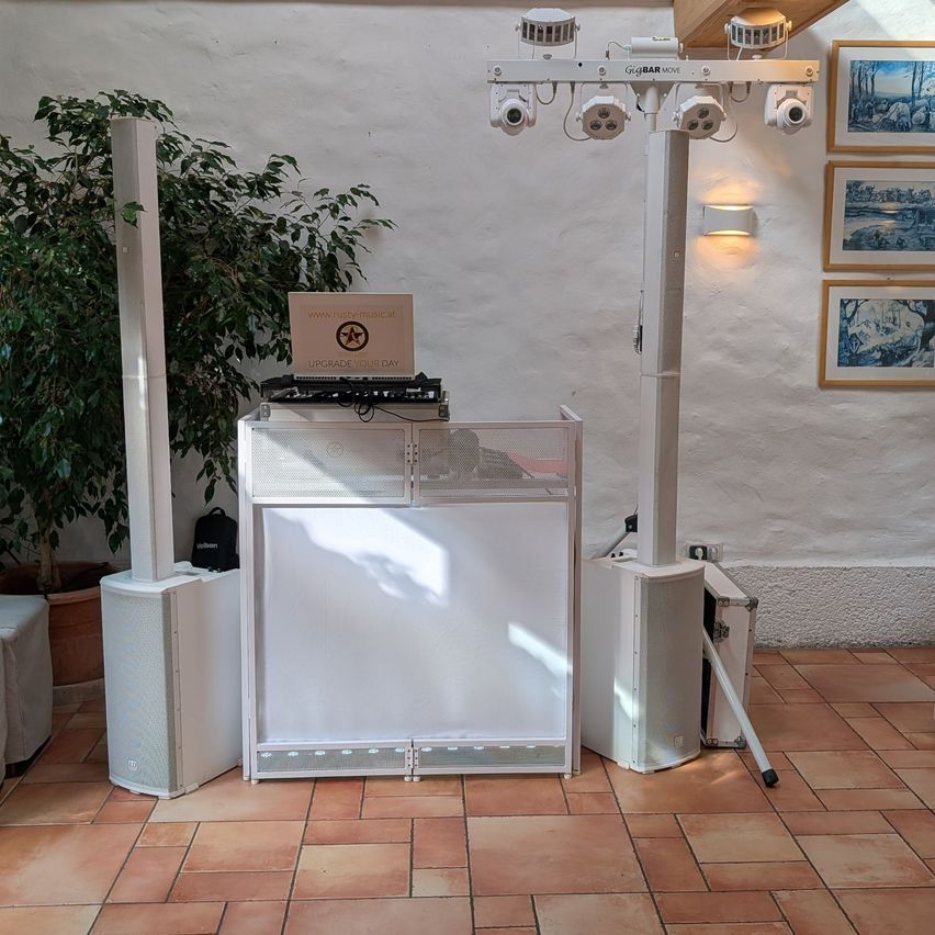 A DJ setup with speakers, a box, and a light fixture in a room.