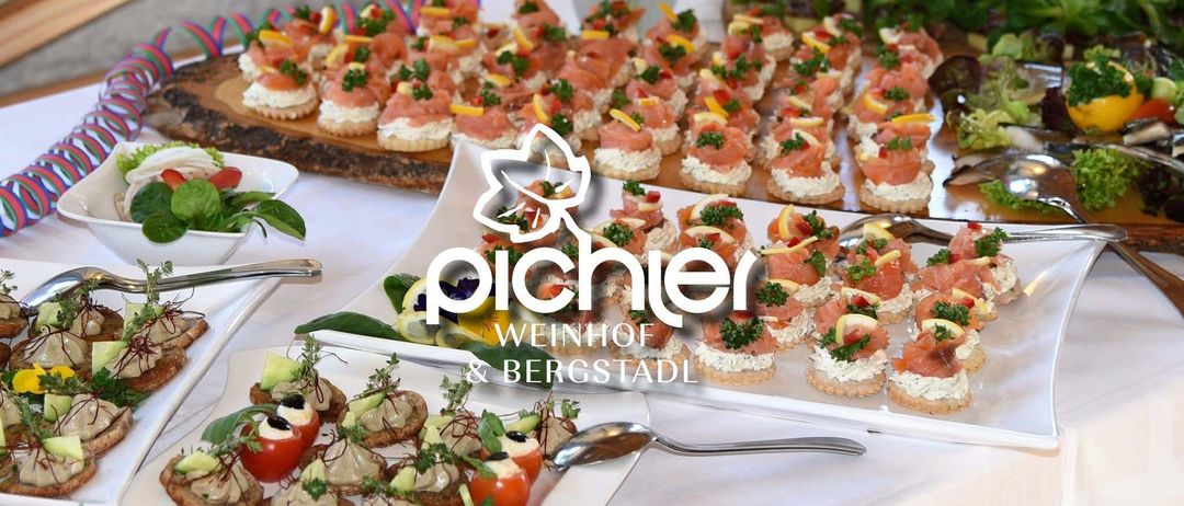 Ein Tisch zeigt mehrere Häppchen, die mit Lachs, Zitrone und Kräutern belegt sind. Ein weißer Teller hat verschiedene Häppchen und einen Löffel. Das Bild hat einen Wasserzeichen 'Pichier Weinhof & Bergstadl'.
