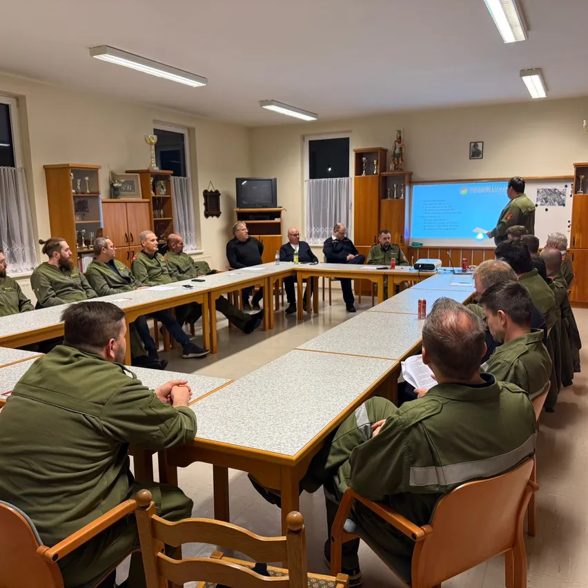 Eine Gruppe von Männern in Militäruniformen sitzt in einem Klassenzimmer um einen Tisch mit einer Projektionsleinwand herum, möglicherweise für eine Besprechung.