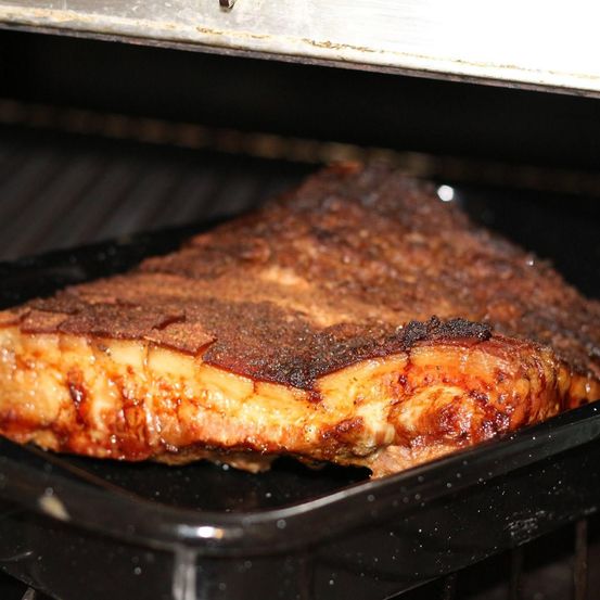 Ein Nahaufnahme eines gut gekochten Steaks auf einem schwarzen Tablett in einem Grill, mit einer knusprigen Außenseite und saftiger Innenseite.