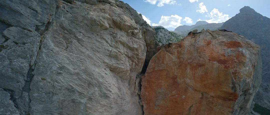 Eine felsige Klippe mit einer tiefen Schlucht und den Worten 'COPTER COOPERATION' darüber. Der Himmel ist blau mit verstreuten Wolken und fernen Bergen.