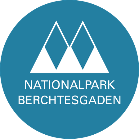 Das Logo für Nationalpark Berchtesgaden. Ein blauer Kreis mit drei weißen Dreiecken vertikal gestapelt und der Name in weiß geschrieben.