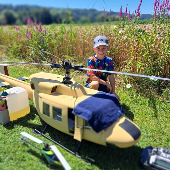 Bild enthält, Grass, Aircraft, Helicopter, Vehicle, Vegetation, Boy, Child, Male, Person, Outdoors