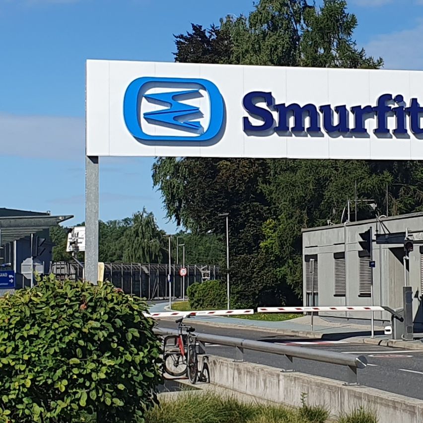 Das Smurfit Westrock-Schild befindet sich auf einem Gebäude mit blauem Himmel und geparkten Autos im Hintergrund.