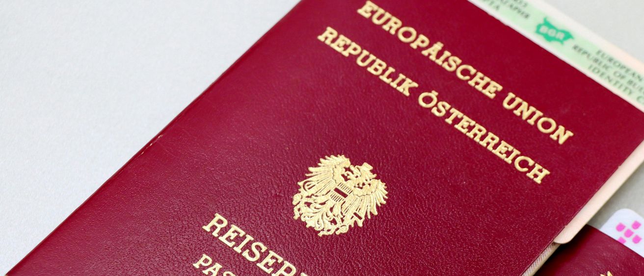 Zwei bordeauxrote Pässe sind ausgestellt. Der obere Pass ist aus der Republik Österreich. Der untere Pass ist aus Portugal.