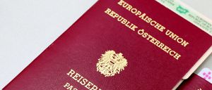 Zwei bordeauxrote Pässe sind ausgestellt. Der obere Pass ist aus der Republik Österreich. Der untere Pass ist aus Portugal.