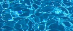 Eine Nahaufnahme eines Pools mit klarem, blauem Wasser. Das Wasser reflektiert Licht und erzeugt Wellen und Wirbel.