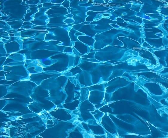 Eine Nahaufnahme eines Pools mit klarem, blauem Wasser. Das Wasser reflektiert Licht und erzeugt Wellen und Wirbel.