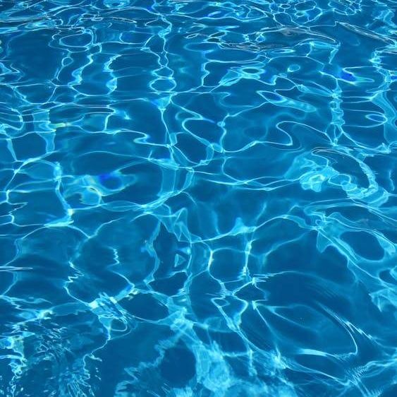 Eine Nahaufnahme eines Pools mit klarem, blauem Wasser. Das Wasser reflektiert Licht und erzeugt Wellen und Wirbel.