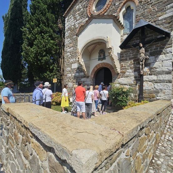 Eine Gruppe von Menschen steht vor einer Kirche mit einem Kruzifix an der Wand.