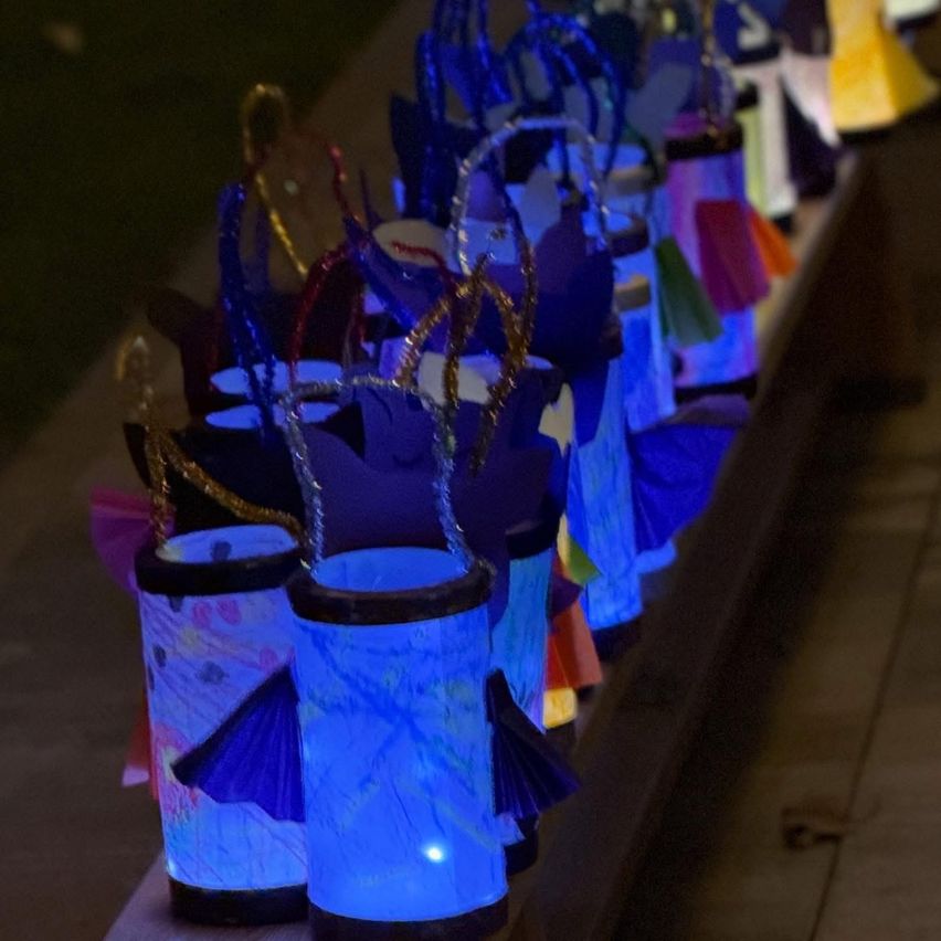 Eine Reihe leuchtender blauer Papierlaternen mit Schmetterlingsflügeln, die im Dunkeln leuchten, auf einer Betonoberfläche aufgereiht.