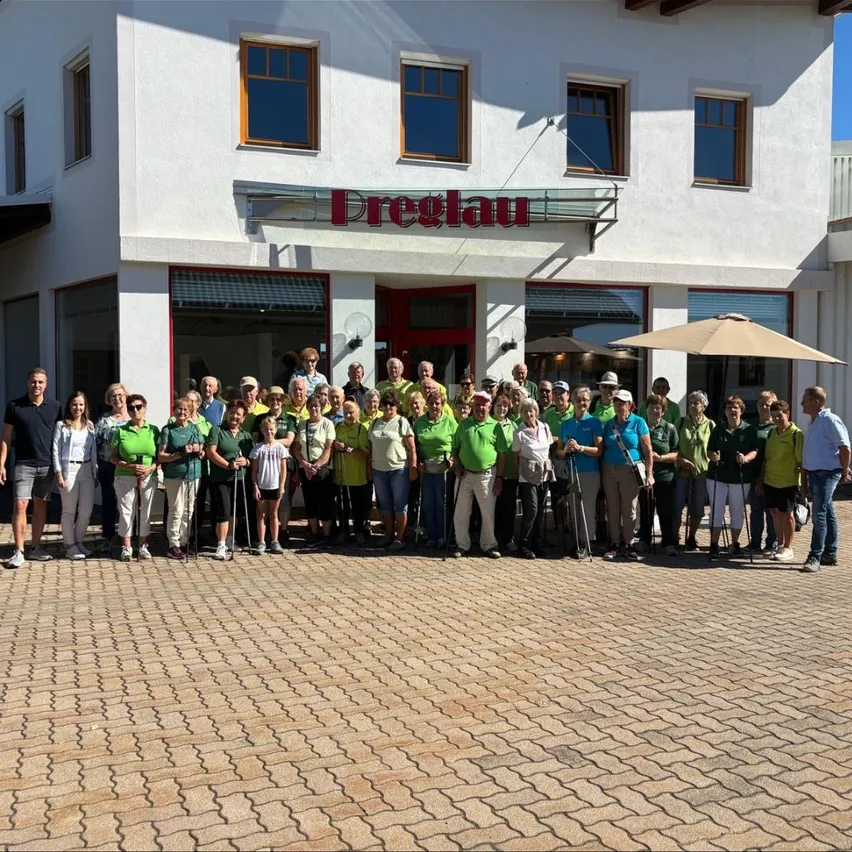 Eine Gruppe von Menschen in grünen Shirts steht vor einem Gebäude mit dem Namen Preglau und posiert für ein Foto.