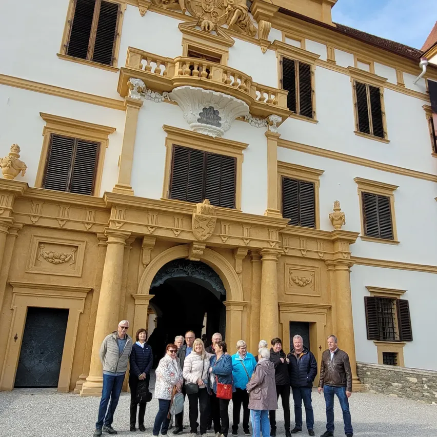 Eine Gruppe von Menschen in Winterkleidung posiert vor einem historischen Gebäude mit kunstvollen architektonischen Details.