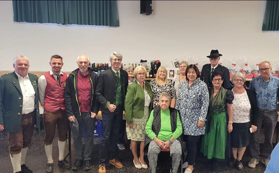 Eine Gruppe von Menschen steht zusammen in einem Raum, einige lächeln und posieren für ein Foto.