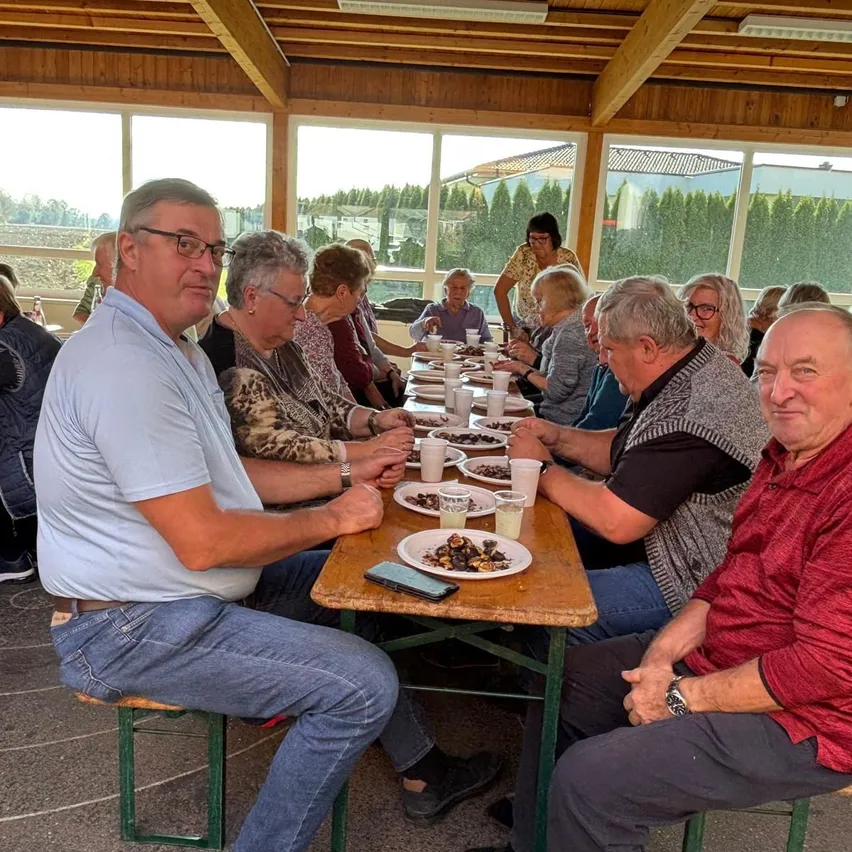 Eine Gruppe von Menschen sitzt an einem Tisch in einem Restaurant. Sie essen und trinken.