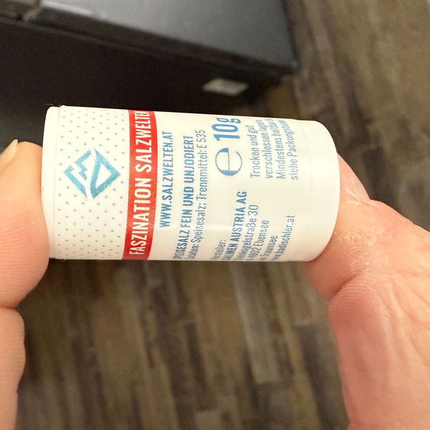 Eine Person hält eine weiße Tube mit blauem Text, der 'Fascination Salzweide' und 'e109' lautet.