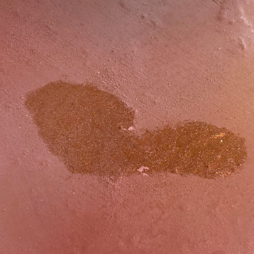 Eine Nahaufnahme einer rosa Oberfläche mit einem auffälligen braunen Fleck, möglicherweise von einem Flüssigkeitsaustritt.