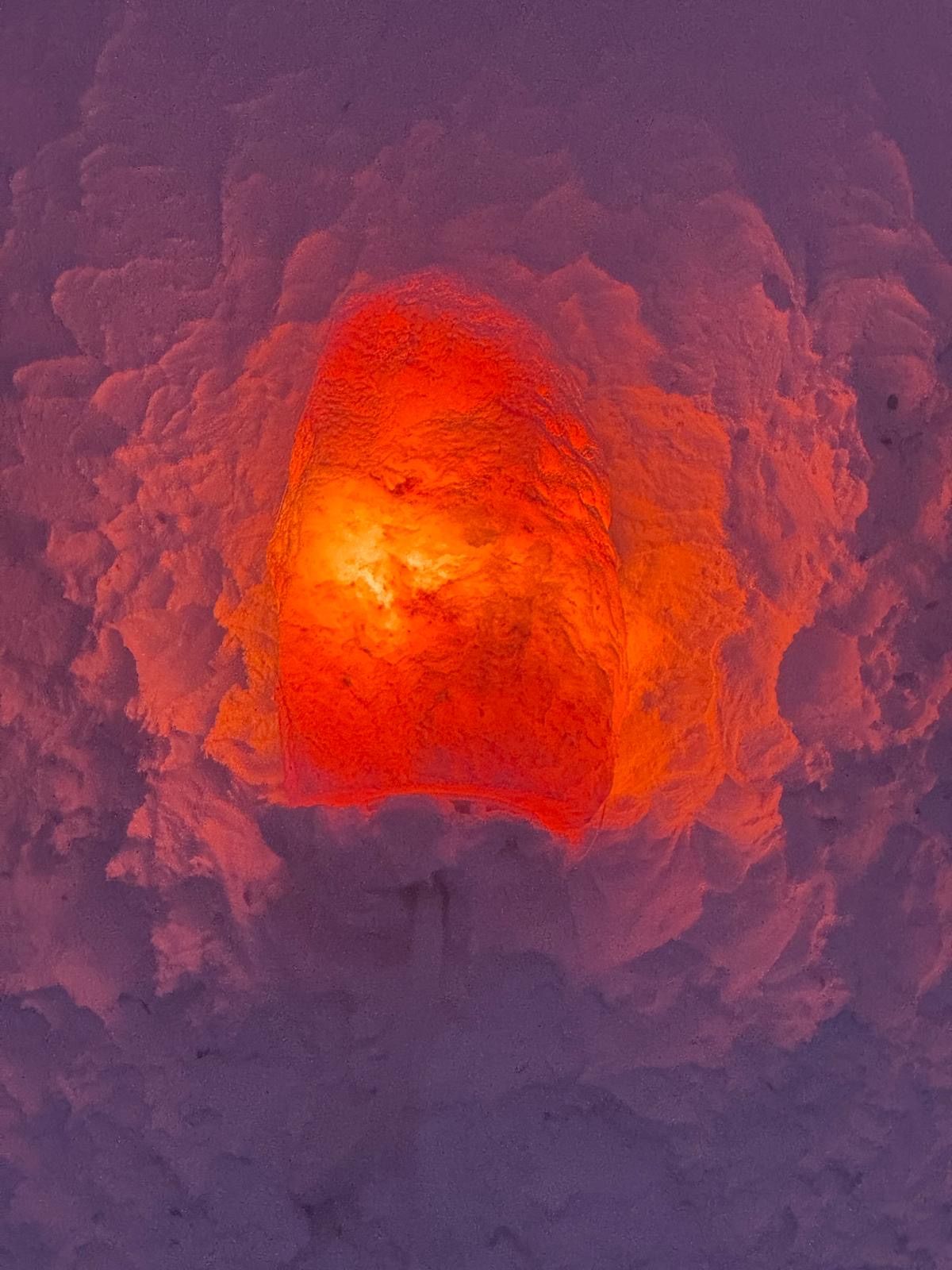 Ein leuchtender orangefarbener Stein ist in eine verschneite Landschaft eingebettet, umgeben von einer kreisförmigen Schneeformation.