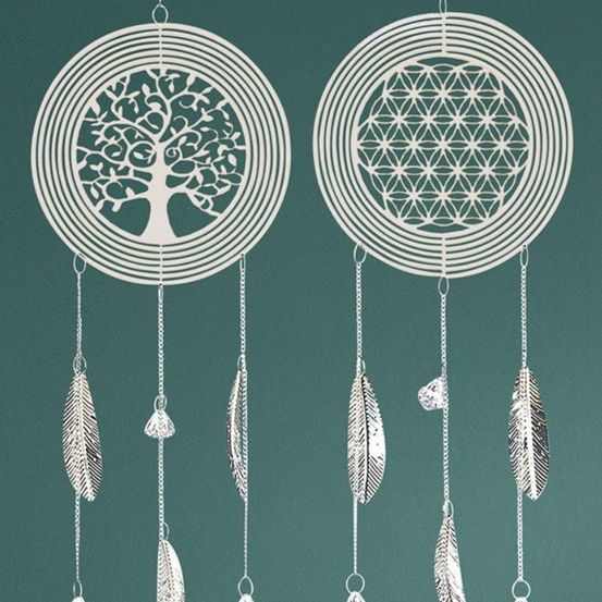 Zwei Traumfänger hängen vor einem türkisfarbenen Hintergrund, jeder mit einem zentralen Design. Links ist ein Baum zu sehen, rechts ein Lebensblume. Federn und Perlen schmücken die Traumfänger.