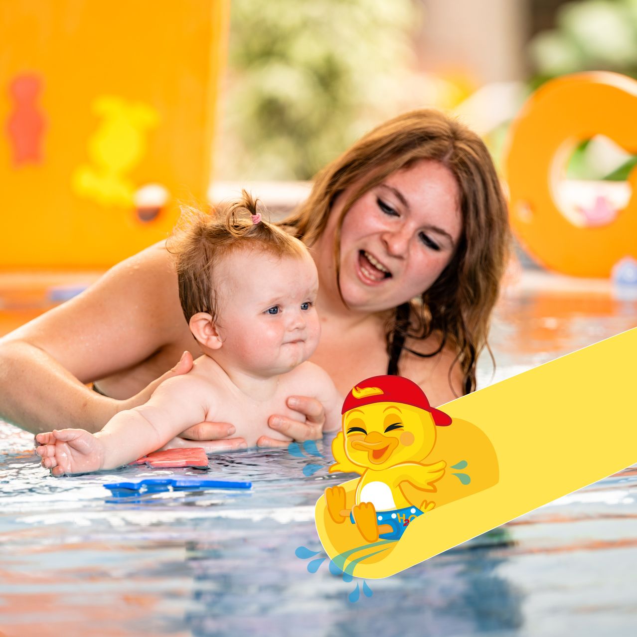 Eine lächelnde Frau hält ein Baby im Pool mit einem gelben Wasserrutsche. Das Baby sieht neugierig aus.