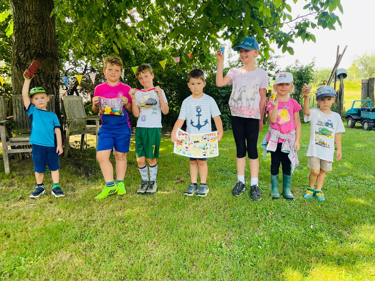 Kinder mit Spielzeug und Buch im Garten