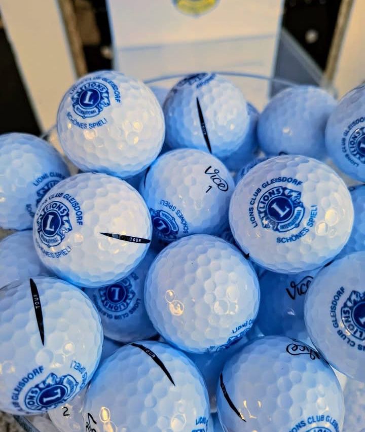 Eine Sammlung von blauen Golfbällen mit dem Lions Club Gleisdorf Logo, nummeriert von 1 bis 10, in einer durchsichtigen Glasschale.