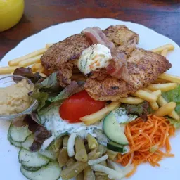Ein Teller mit Fleisch, Pommes, Salat und Gemüse auf einem Holztisch.