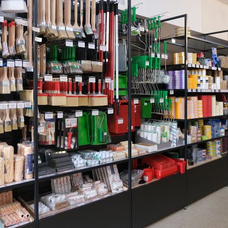 Ein Geschäft mit Regalen, die verschiedene Werkzeuge wie Pinsel, Walzen und Aufbewahrungsbehälter in verschiedenen Farben und Typen präsentieren.