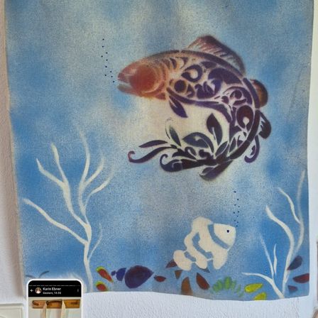 Ein Unterwassergemälde zeigt einen großen Fisch in kunstvollem Design, der über einem Korallenriff schwimmt. Kleinere Fische und Meerespflanzen sind darunter. Das Bild wurde mit einem Smartphone aufgenommen.