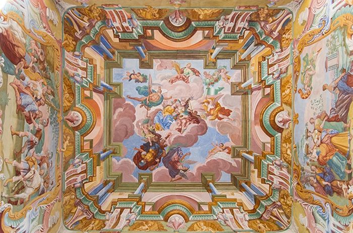 Das Innere eines kuppelförmigen Raums mit einem farbenfrohen Fresko an der Decke, das verschiedene Figuren und Elemente in einem lebendigen Stil darstellt.