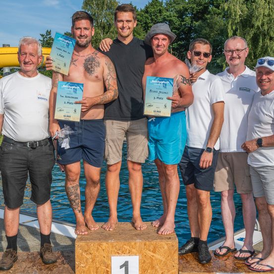 Sechs Männer stehen neben einem Pool und posieren für ein Foto mit Urkunden in den Händen. Der erste Platz ist links, der zweite Platz in der Mitte und der dritte Platz rechts.