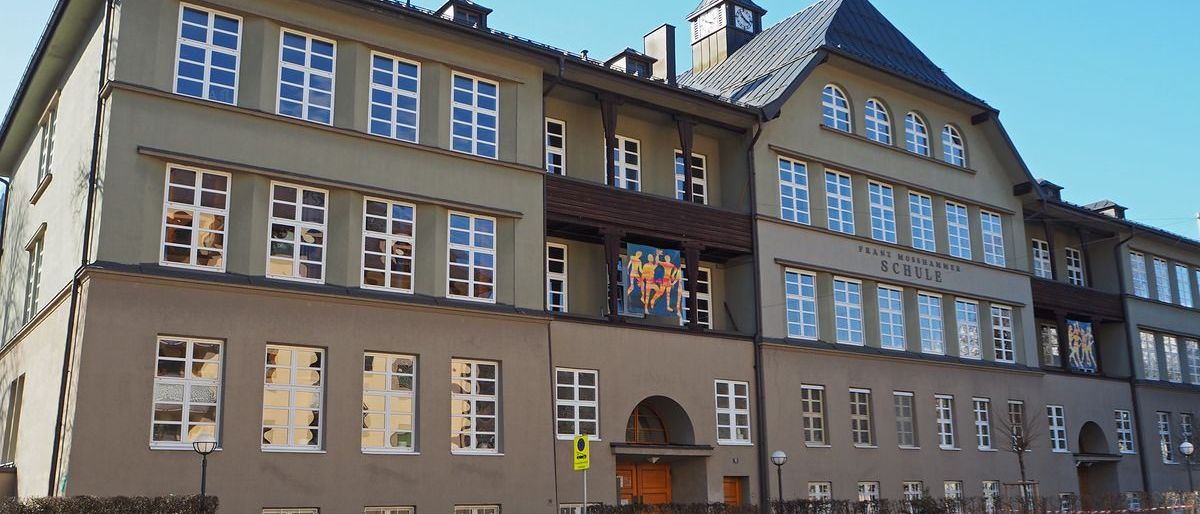 Die Vorderseite des Franz-Mehring-Schule-Gebäudes, ein mehrstöckiges Schulgebäude mit vielen Fenstern und einem Glockenturm.