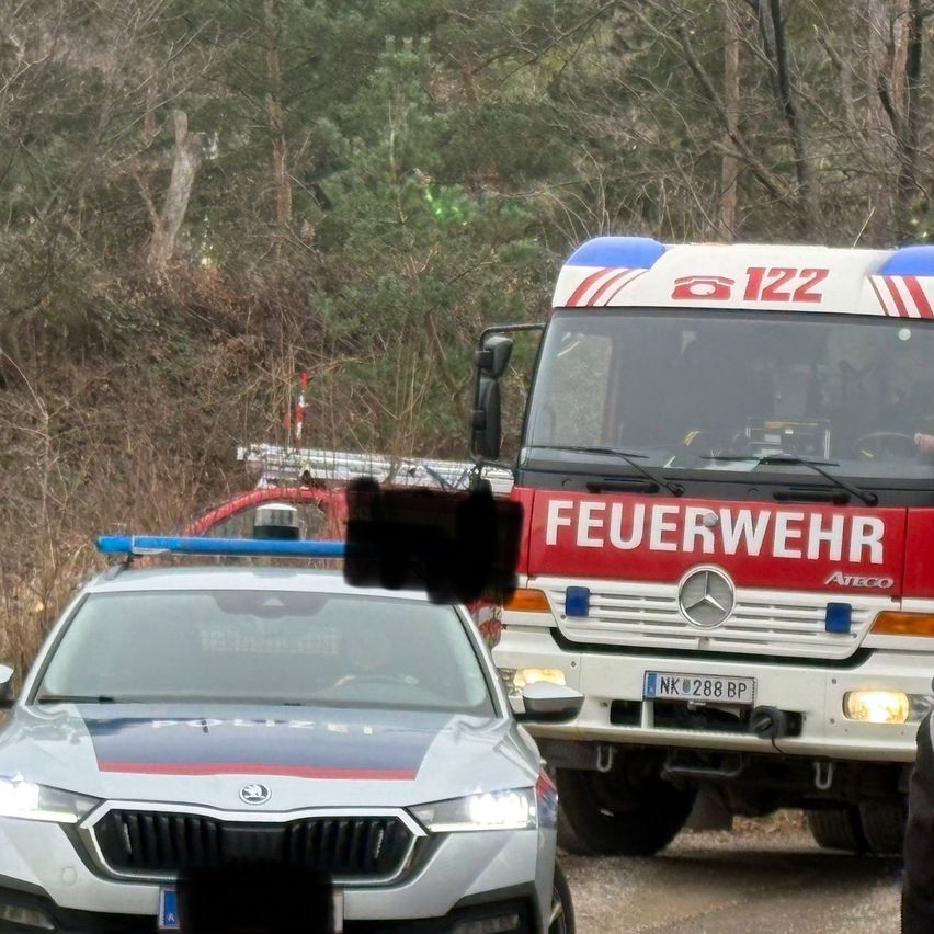 Ein Polizeiauto ist vor einem Feuerwehrauto mit der Nummer 122 auf der Vorder- und Seitenseite geparkt. Das Feuerwehrauto hat ein rot-weißes Farbschema und ist auf einer Straße geparkt.