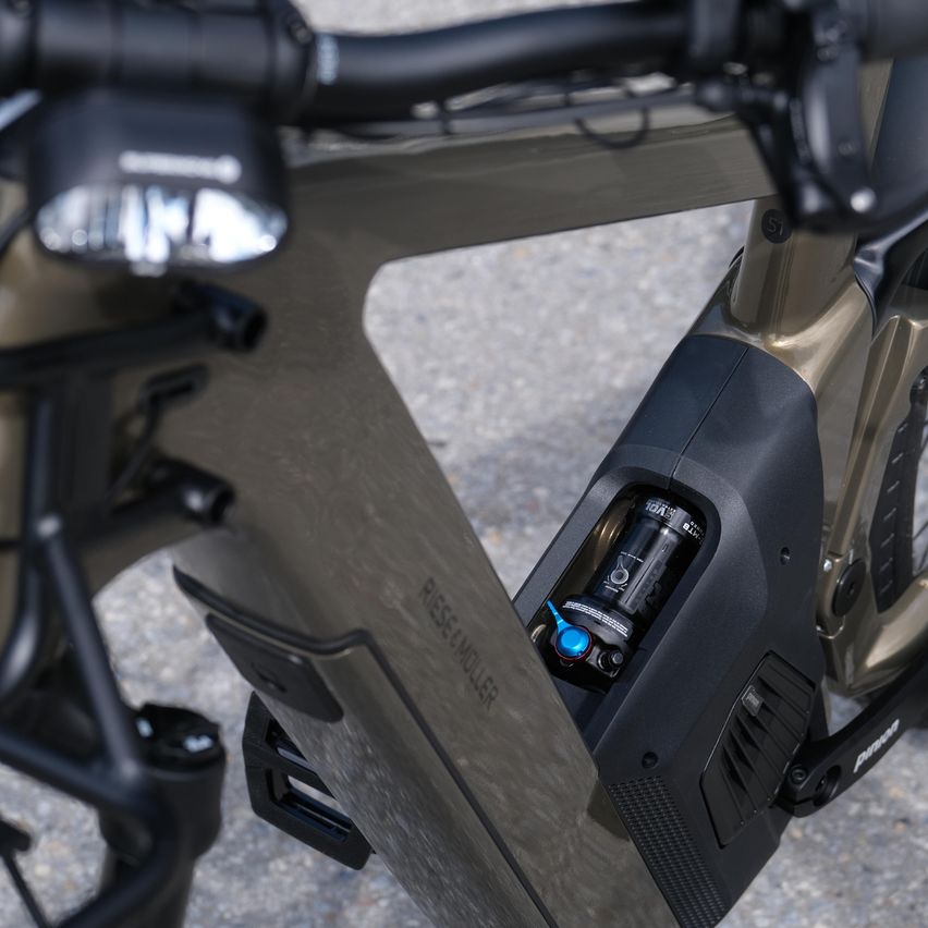 Eine Nahaufnahme eines Fahrrads mit schwarzem Lenker, silbernem Akzent und Batteriefach mit einer Batterie darin. Das Fahrrad hat auch eine Frontleuchte, eine Kette und ein Pedal.