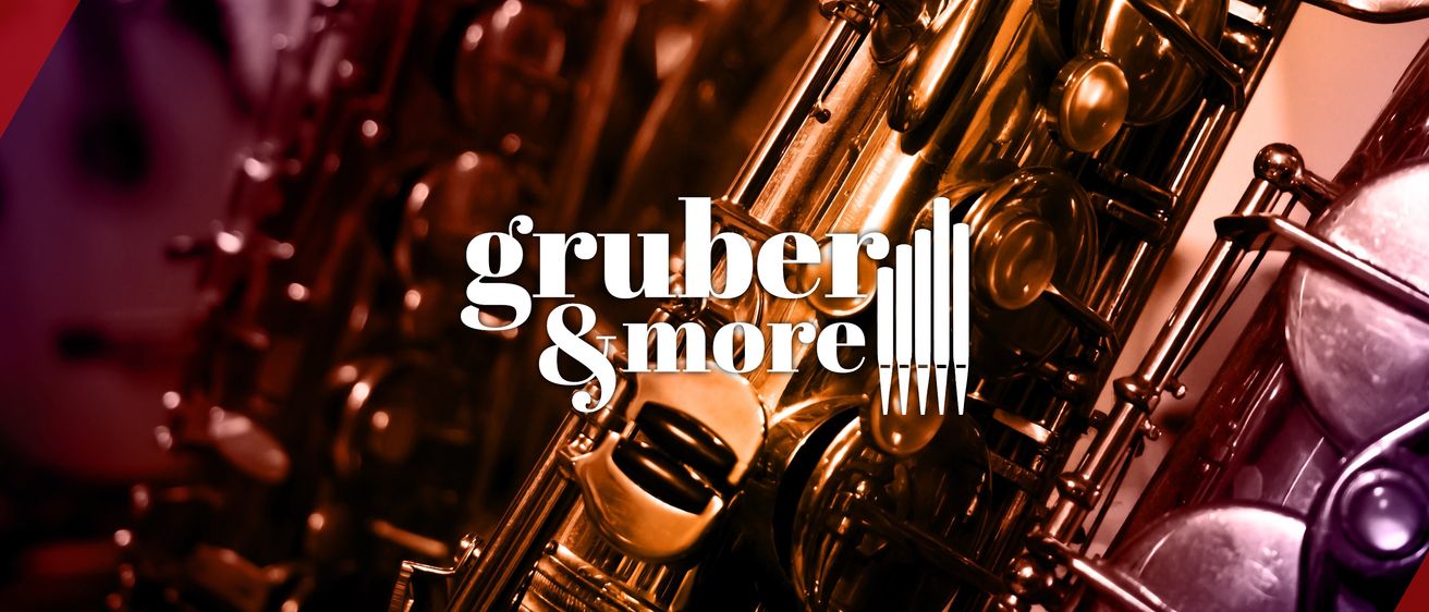 Ein Nahaufnahme eines Saxophons mit dem Text 'Gruber & More' prominent angezeigt. Das Saxophon hat einen goldenen Farbton, mit sichtbaren Details wie Tasten und Mundstück. Der Hintergrund ist dunkel, was auf ein Studio oder Aufführungsumgebung hindeutet.