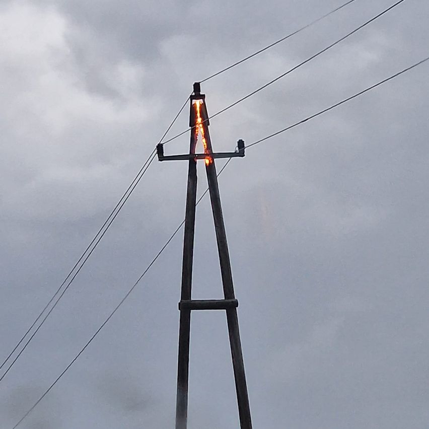 Ein Strommast mit einem Feuer an der Spitze an einem bewölkten Tag.