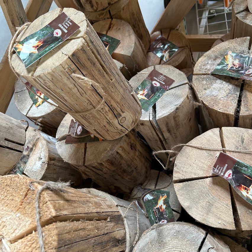 Ein Stapel Holzscheite mit Etiketten darauf, möglicherweise für Feuerholz. Jeder Baumstamm hat ein Etikett mit einem Feuerbild. Das Holz sieht aus, als wäre es gelagert und einsatzbereit.