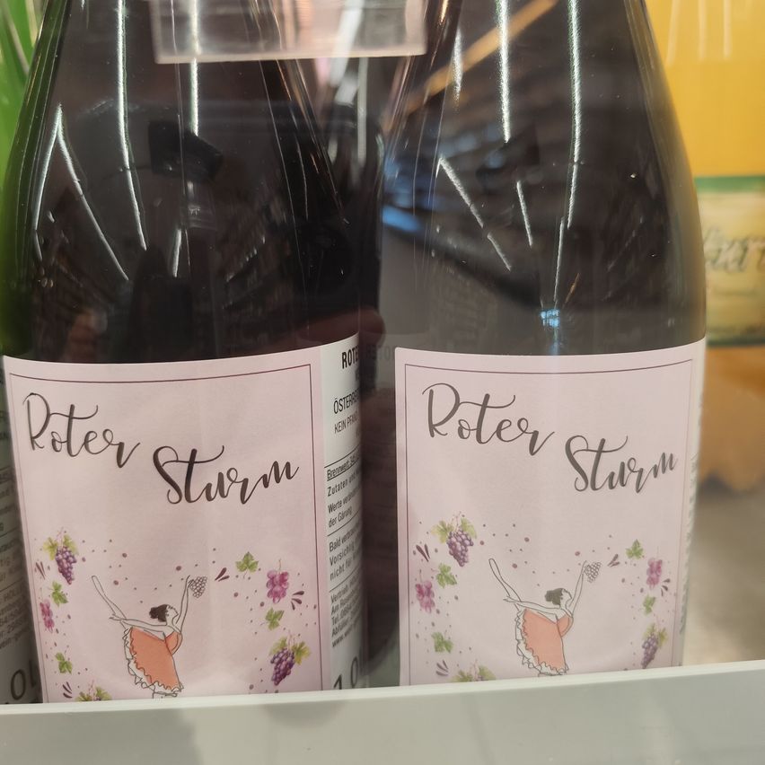 Two bottles of Roter Sturm wine displayed on a shelf, featuring a dancer and grapes on the label.