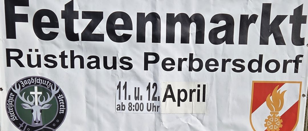 Ein weißer Banner mit schwarzen Texten lautet 'Zennmaier Haus Perber'. Darunter steht '11. u. 12. April ab 8:00 Uhr'. Das Banner hängt von einem Metallpfosten.