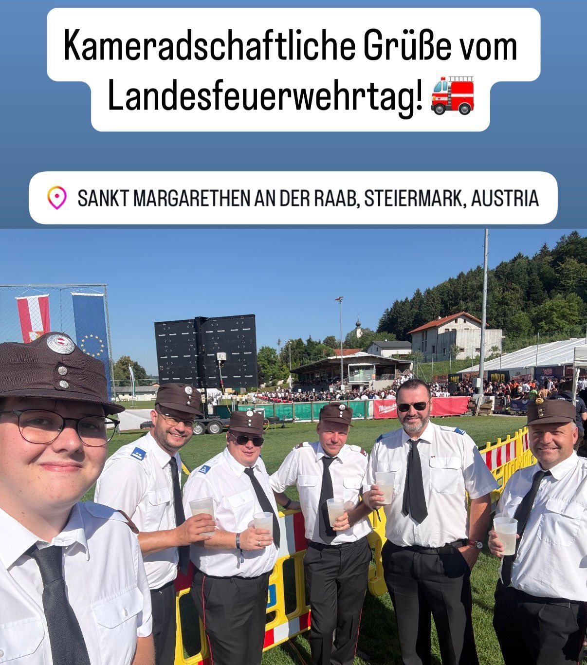 Fünf Männer in Uniform stehen draußen auf einem Grasfeld und posieren für ein Foto in Sankt Margarethen an der Raab, Österreich. Sie halten Tassen und lächeln.