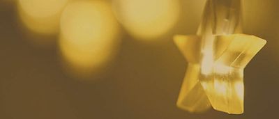 Eine Nahaufnahme einer gelben sternförmigen Glühbirne, die sanft leuchtet, mit anderen Lichtern, die im Hintergrund schwach sichtbar sind.