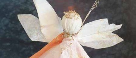 Eine handgefertigte Engelsdekoration aus Papier, die einer Muschel ähnelt, mit Flügeln, hängt von einem Ast. Es ist wahrscheinlich eine Weihnachtsdekoration.