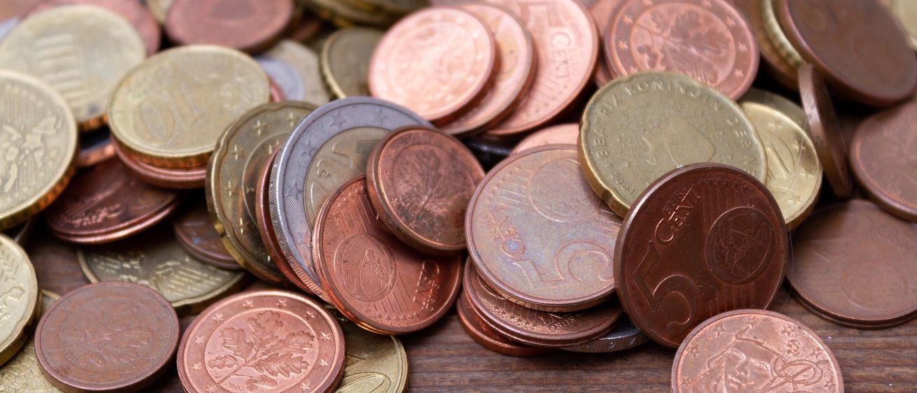 Ein Haufen verschiedener Euro-Münzen, einschließlich 1, 2, 5, 10, 20 und 50 Cent Münzen, auf einer Holzoberfläche.