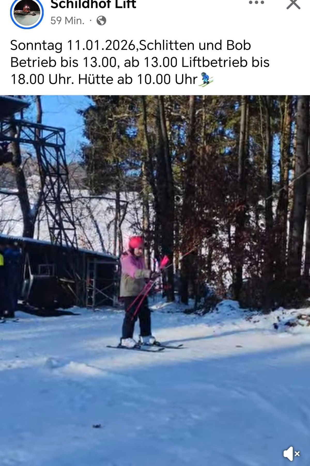 Ein Skifahrer in einer pinken Mütze und Jacke hält Skistöcke, während er einen schneebedeckten Hang hinunterfährt. Im Hintergrund sind Bäume und eine Hütte zu sehen.