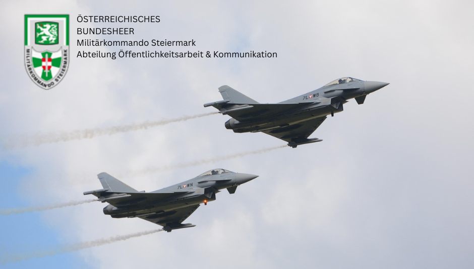 Ein Bild mit zwei Militärjets, die mit Rauchspuren am Himmel fliegen, vor einem bewölkten Hintergrund. Der obere Jet hat die Markierung '7L WB' und der untere '7L WN'. Über den Jets befindet sich ein Logo mit dem Text 'Osterreichisches Bundesheer Militatkommando Steiermark Abteilung Offentlichkeitsarbeit & Kommunikation'.