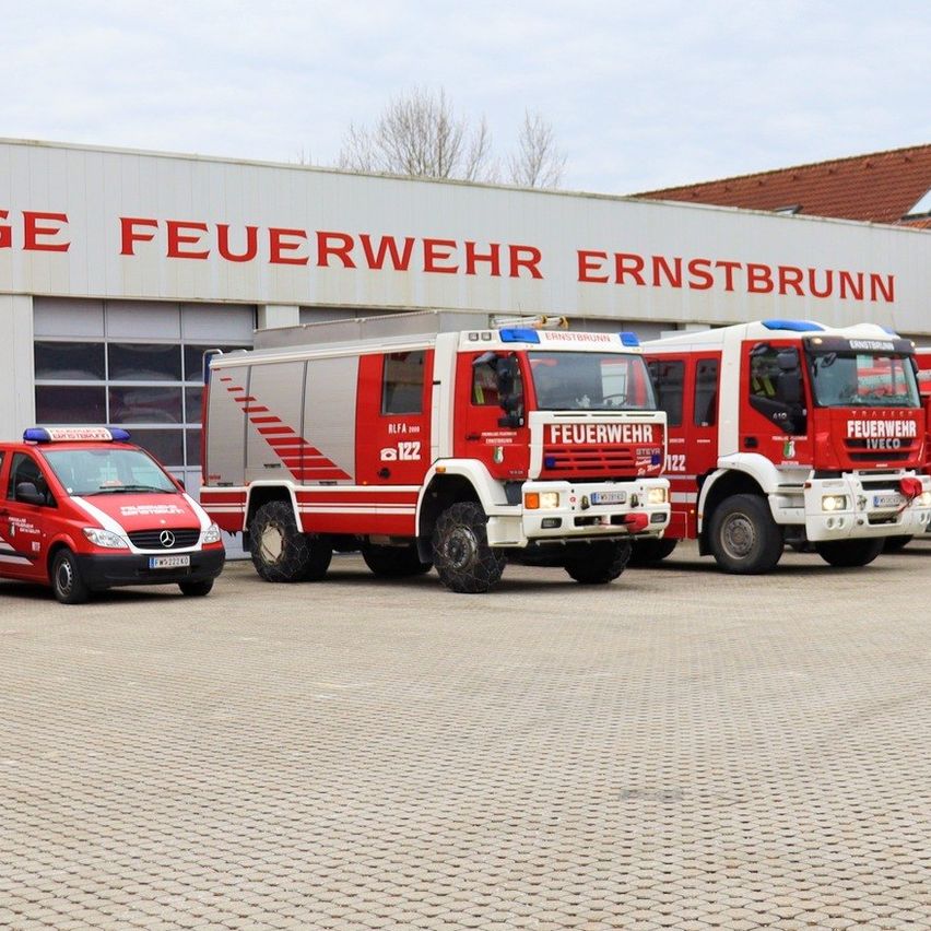 Rote Feuerwehrwagen vor der Feuerwache Ernstbrunn unter einem bewölkten Himmel geparkt.