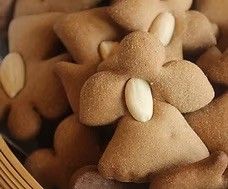 Ein Nahaufnahme von einem Korb voller Lebkuchen-Engel-Kekse, jeder mit einer Mandel gekrönt.