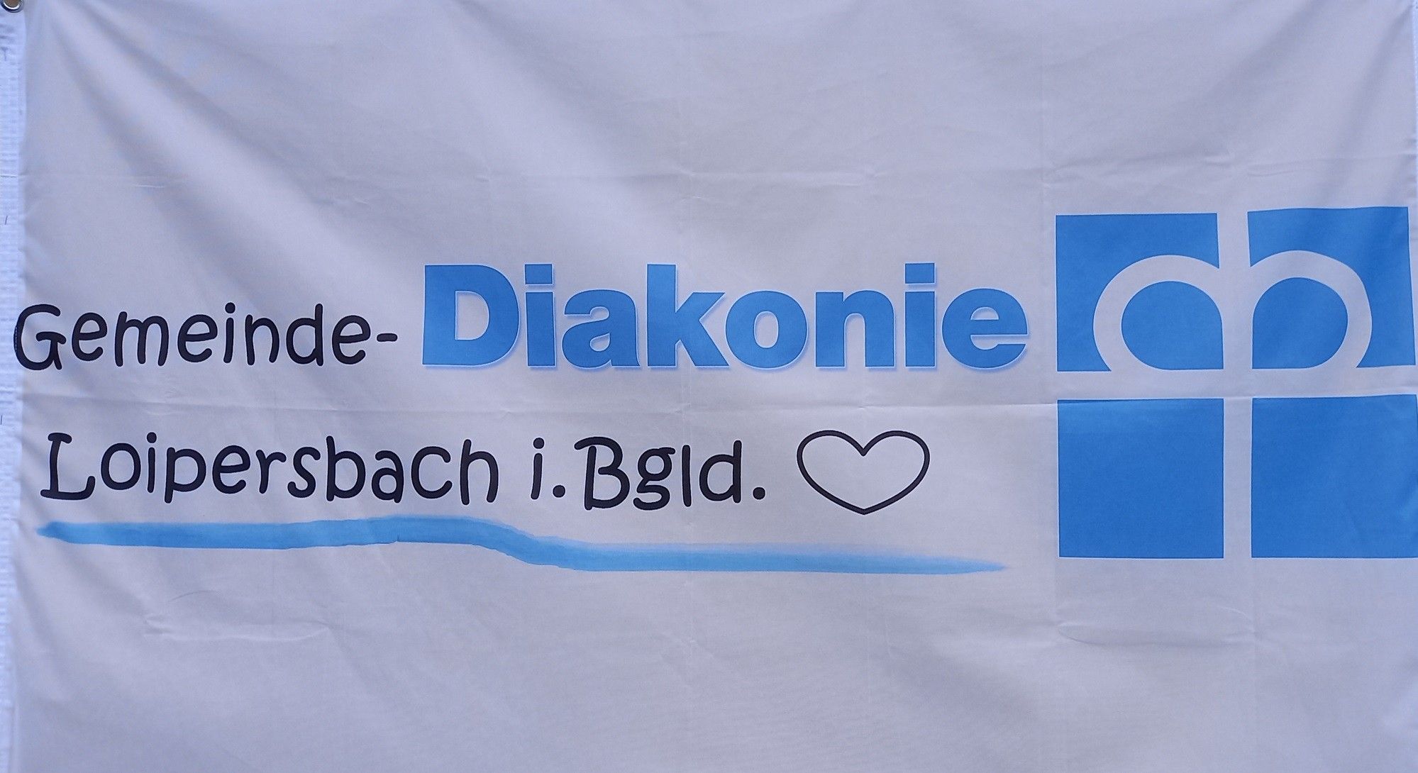 Ein weißes Banner mit blauem Text, der 'e-Diakonie bach i. Bgld.' und ein Herzsymbol zeigt. Der Text ist klar und gut komponiert.