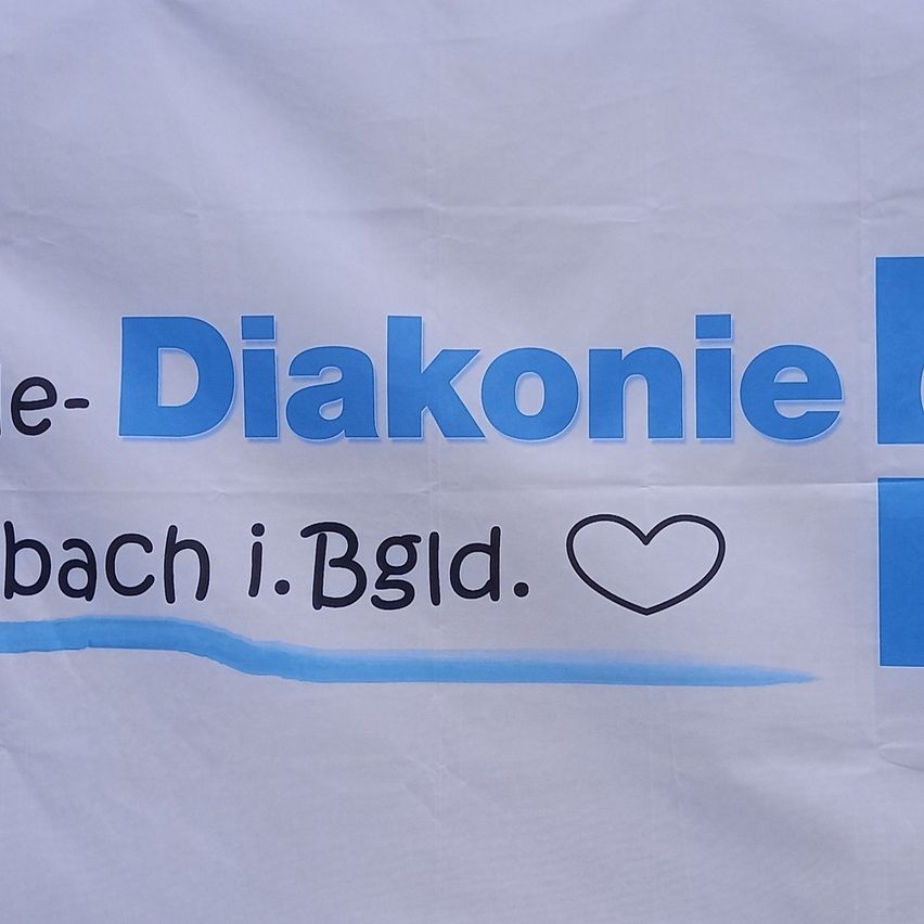 Ein weißes Banner mit blauem Text, der 'e-Diakonie bach i. Bgld.' und ein Herzsymbol zeigt. Das Banner hat eine blaue Linie am unteren Rand.