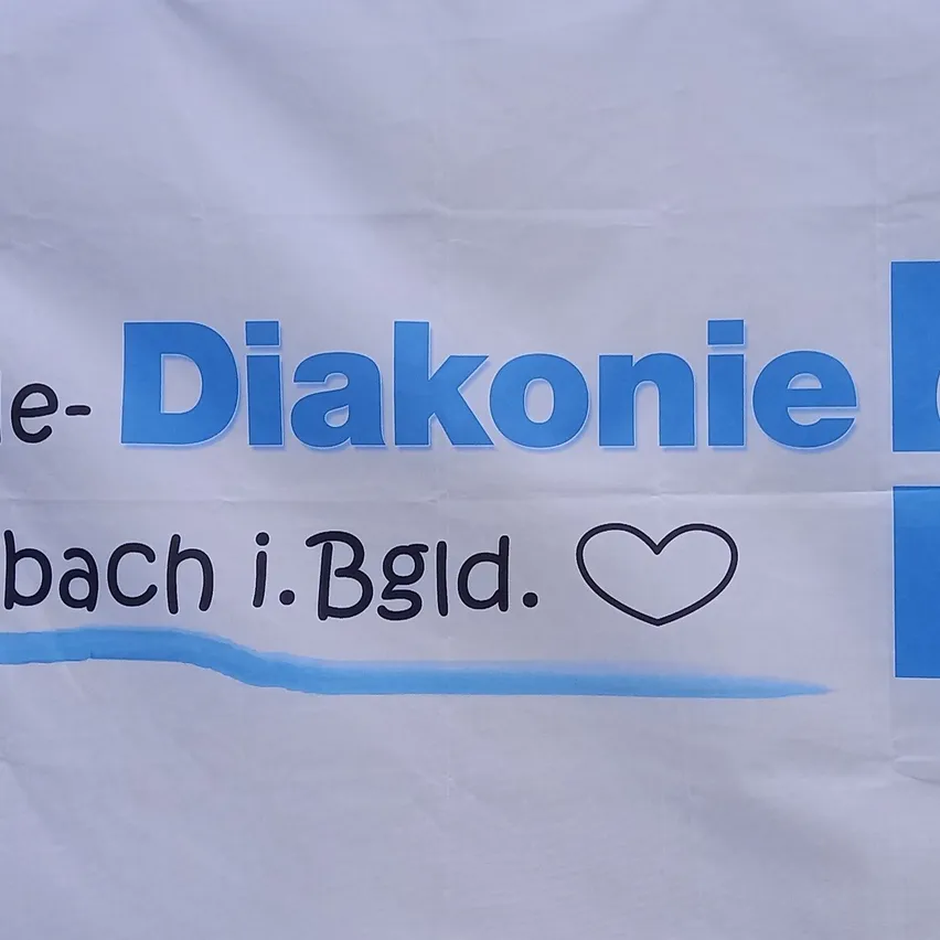 Ein weißes Banner mit blauem Text, der 'e-Diakonie bach i. Bgld.' und ein Herzsymbol zeigt. Das Banner ist sauber und gut beleuchtet.